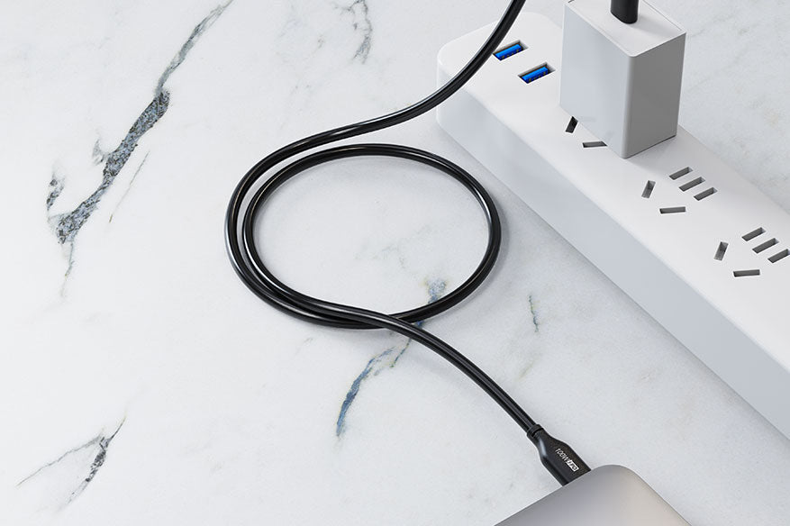 Black USB-C charging cable connected between a laptop and a separate USB-C power adapter.